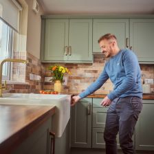 Customer Emmet Laffan in his Oslo Sage kitchen. Wood effect worktop, gold tap, copper handles and Belfast sink.