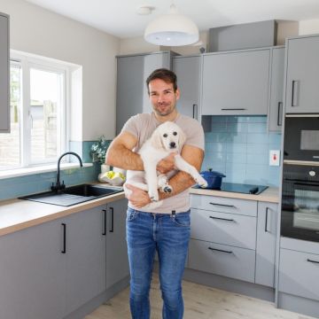 Man with golden retreiver puppy in a modern light grey kitchen