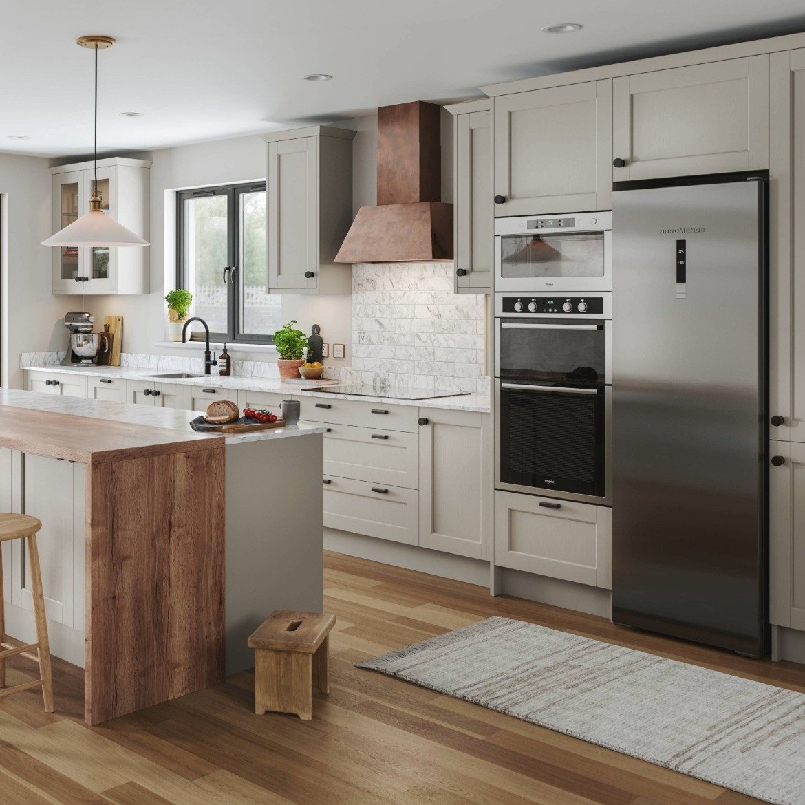 Dereham Taupe kitchen with corner of island, cabinets behind. Design includes Chloe Copper hood, double oven and a large fridge