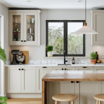 View of Dereham Taupe kitchen, background glass cabinet, window, tap and countertop, foreground island with waterfall edge on worktop