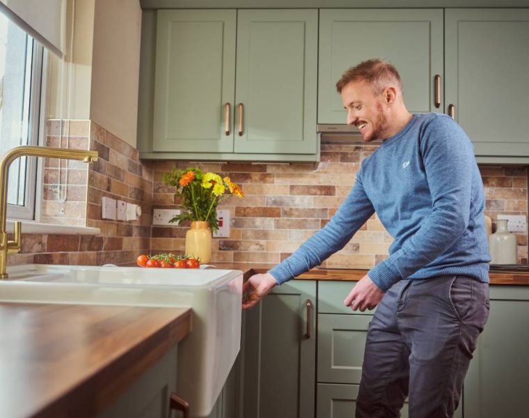 Customer Emmet Laffan in his Oslo Sage kitchen. Wood effect worktop, gold tap, copper handles and Belfast sink.