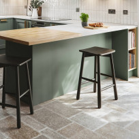 A kitchen peninsula in the Oslo Sage kitchen style. A white work top with a solid oak accent at the end of the penisula.