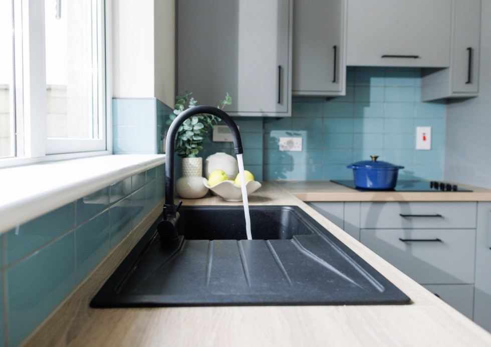 Black running tap with black sink in modern grey kitchen