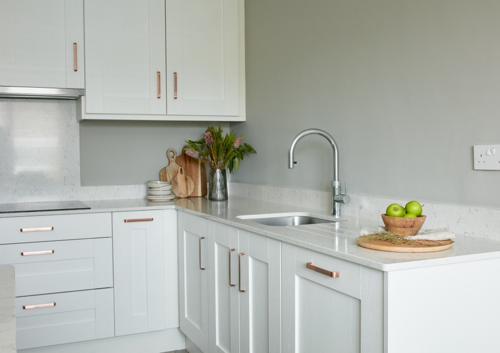Corner of Augusta White kitchen. White worktops, copper handles and chrome tap.